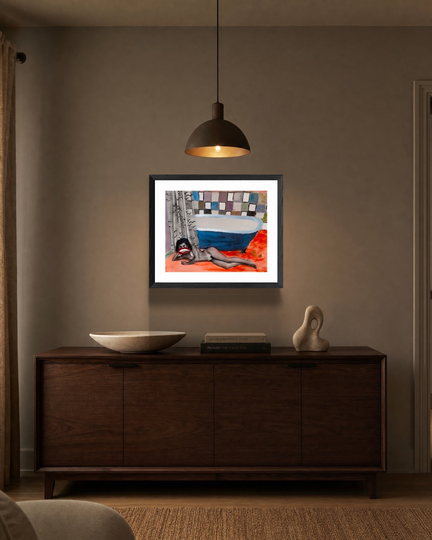 Framed artwork on a wall above a wooden cabinet in a room.